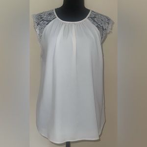 White polyester blouse with lace capped sleeves. Button closure at neck in back.